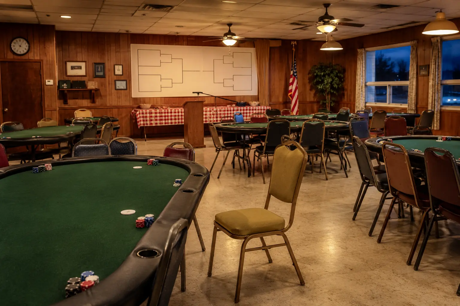 A welcoming community hall prepared with green felt poker tables and simple chairs before an amateur tournament